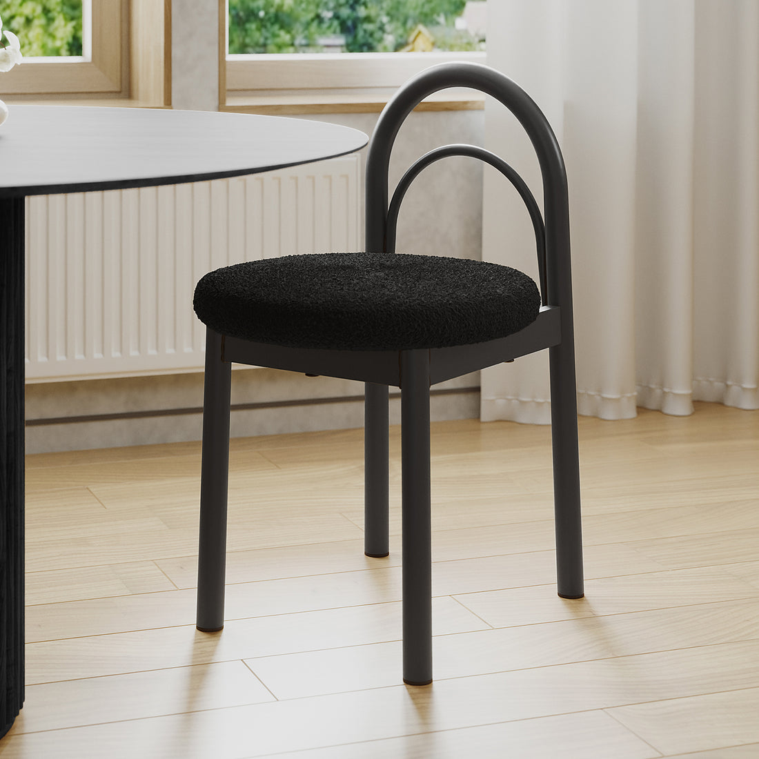 Gilles Boucle Arched Dining Chair Black Set of 2, featuring a double-arched backrest and upholstered seat, positioned next to a dining table, highlighting its elegant design and sturdy metal construction.