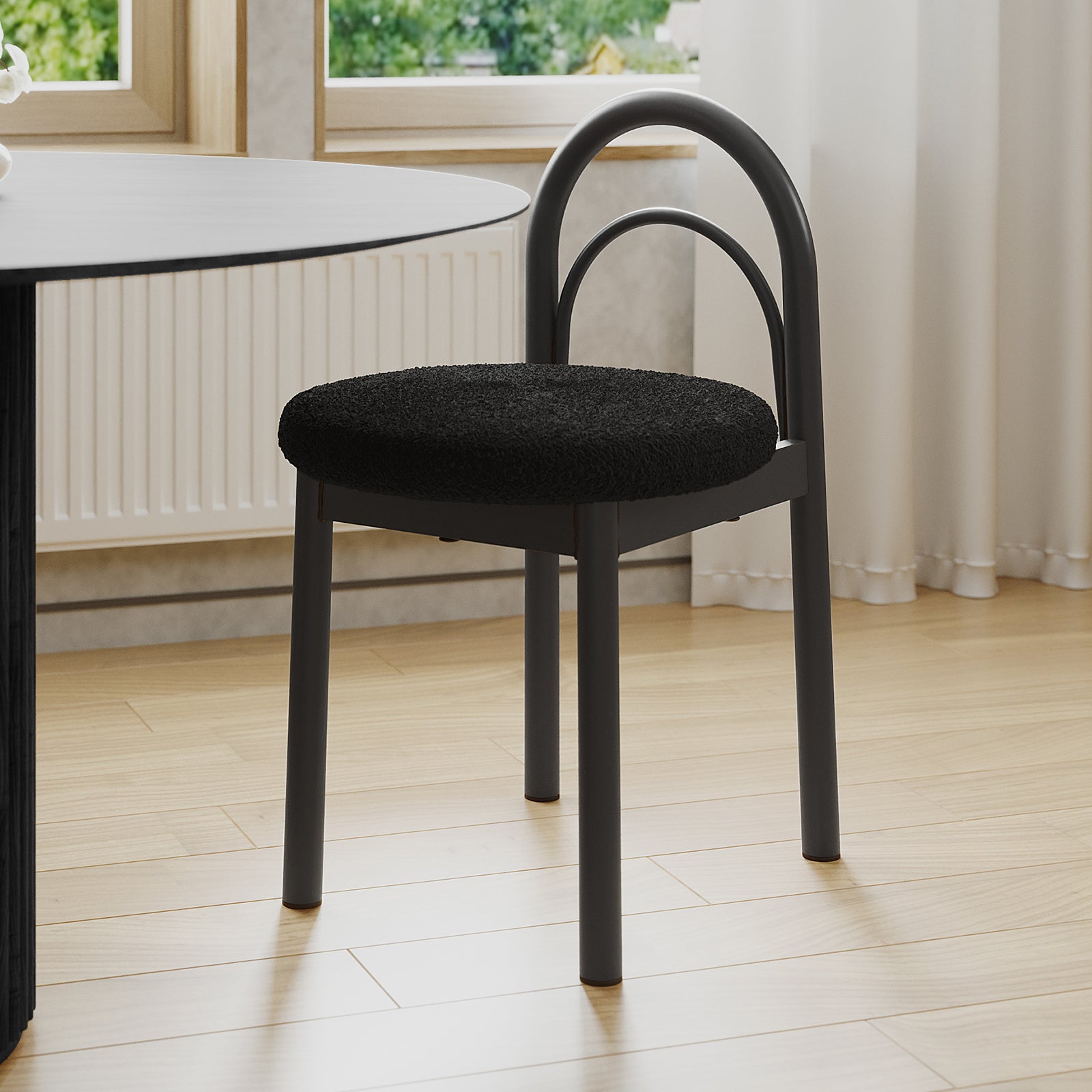 Gilles Boucle Arched Dining Chair Black Set of 2, featuring a double-arched backrest and upholstered seat, positioned next to a dining table, highlighting its elegant design and sturdy metal construction.