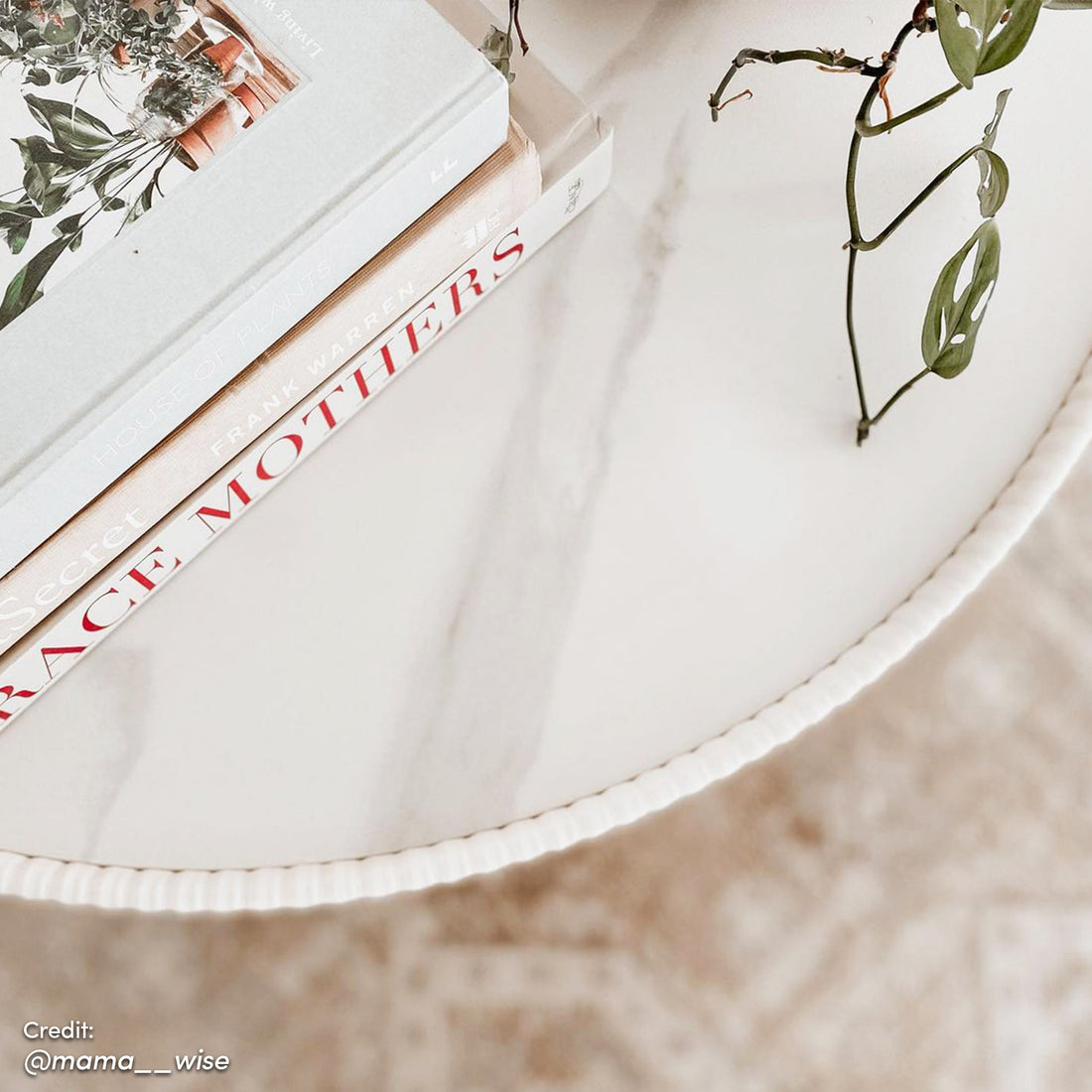 Glalie 70cm Sintered Stone Coffee Table in cream white with a smooth, rounded design, supported by a sturdy gold stainless steel base, showcased on a surface with a stack of books.