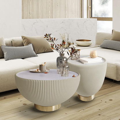 Glalie Sintered Stone Coffee Table Set in Cream White, featuring round, fluted tables with brass-tone bases, adorned with a small tray, vases, a geometric ornament, books, and a lit candle.