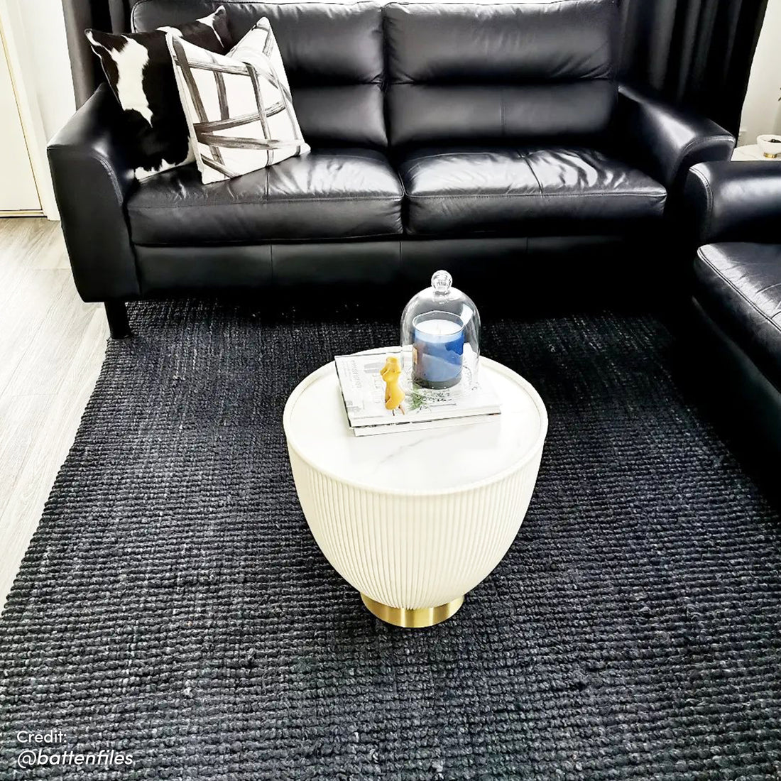 Glalie 47cm Sintered Stone Coffee Table in Cream White, a round fluted drum design on a low brass base, topped with books and a yellow bunny figurine under a glass cloche.