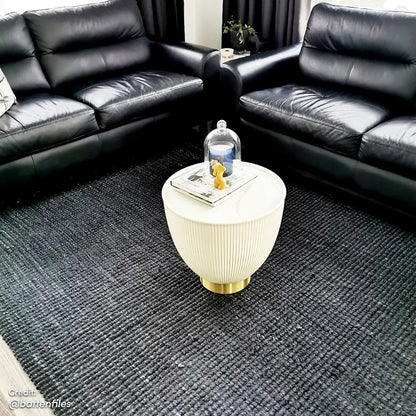 Glalie 47cm Sintered Stone Coffee Table in Cream White, featuring a pleated side design with a brass-tone base, topped with books, a yellow bear-shaped candle, and a glass cloche.