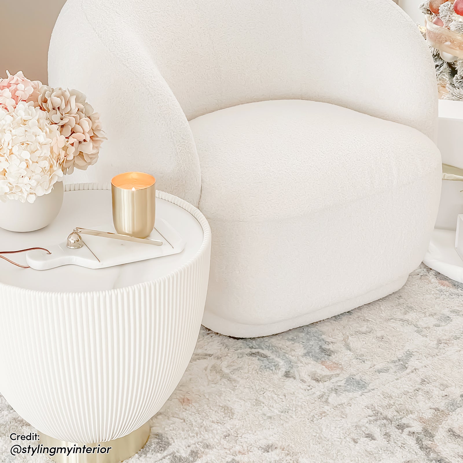 Glalie 47cm Sintered Stone Coffee Table in Cream White, featured with a rounded design and brass-tone base, complements the cozy nook with a boucle armchair and decorative accents.