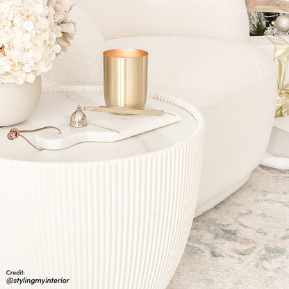 Glalie 47cm Sintered Stone Coffee Table in Cream White with a fluted-edge marble-look top, styled with a brass candle, hydrangeas in a vase, on a pastel-toned rug.
