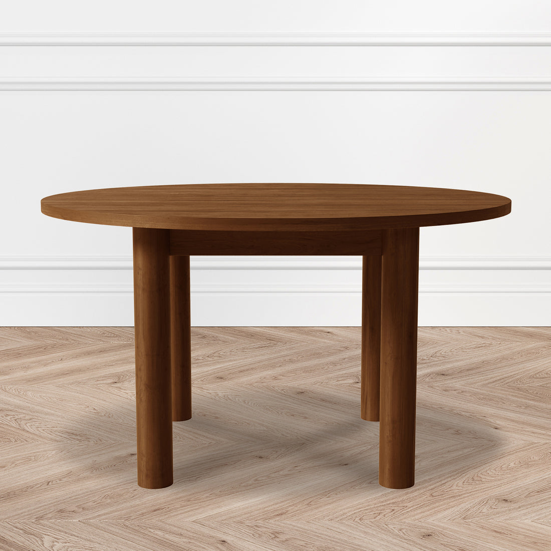 Hudson 80cm Round Hardwood Coffee Table in Walnut features a smooth, walnut-toned top with three sturdy cylindrical legs, set against a chevron-patterned wood floor and white paneled wall.