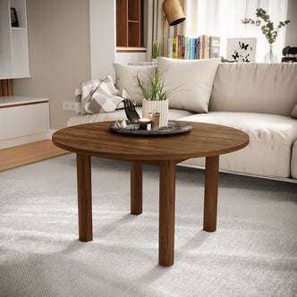 Hudson 80cm Round Hardwood Coffee Table in Walnut, featuring a round wooden design with four cylindrical legs, topped with a dark tray, potted plant, and candle, set in a modern living room.