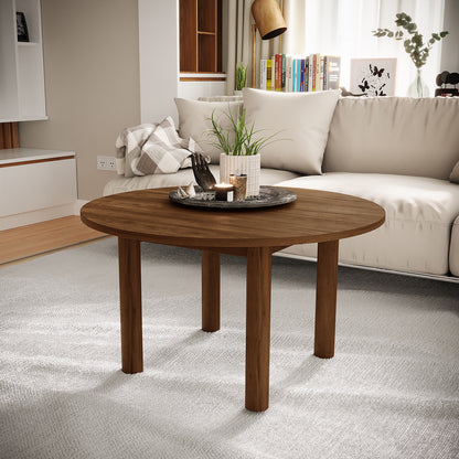 Hudson 80cm Round Hardwood Coffee Table in Walnut, featuring a round wooden design with four cylindrical legs, topped with a dark tray, potted plant, and candle, set in a modern living room.