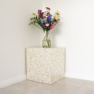 Irene Mother of Pearl Inlay Side Table in Cream featuring hand-crafted mosaic tiles, topped with a clear vase holding a colorful bouquet of mixed flowers, against a neutral-toned room backdrop.