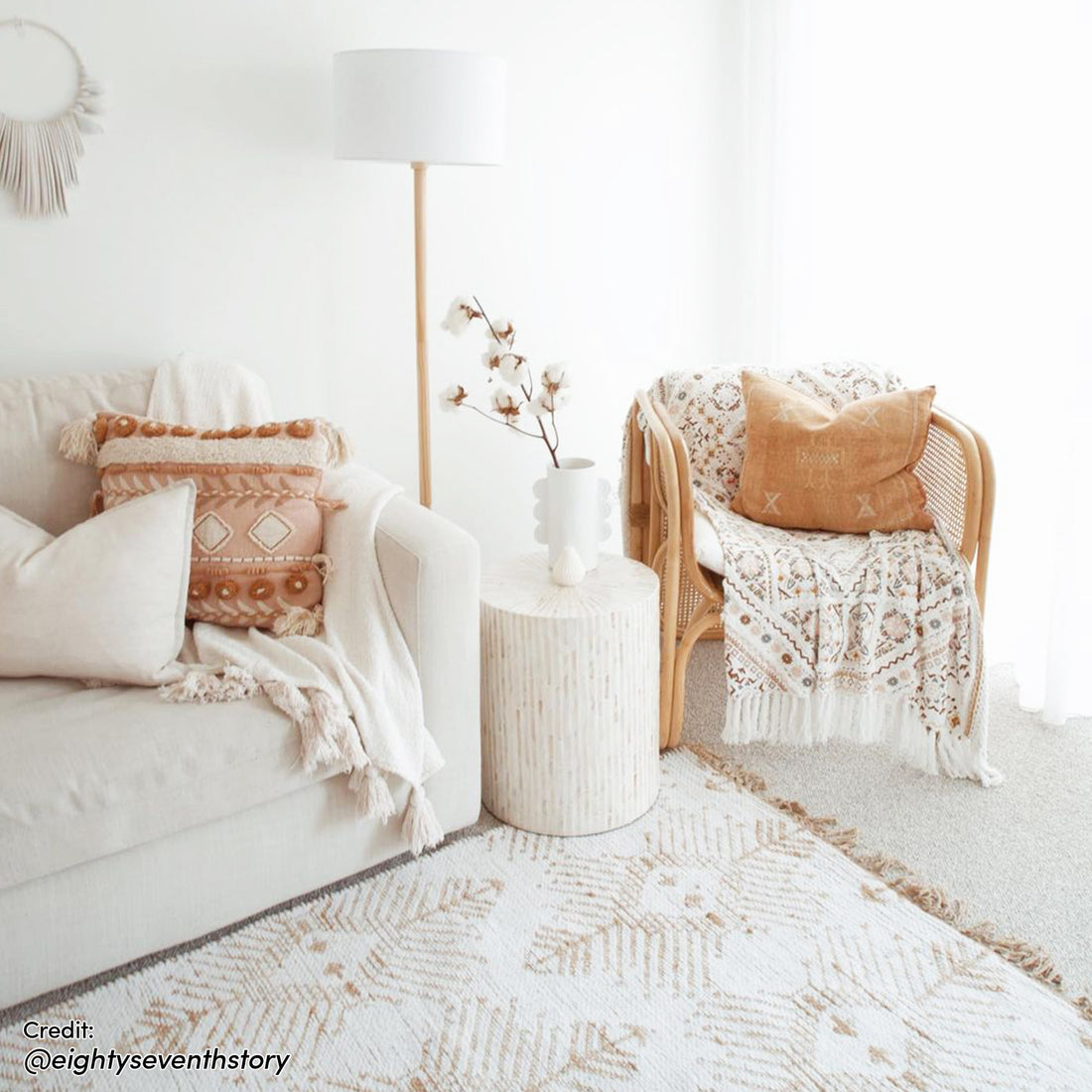 Ivo Mother of Pearl Inlay Side Table in Cream, with shell-like finish, supports a sculptural vase. Its striped design and handcrafted mosaic inlay enhance the room's cozy, boho-modern aesthetic.