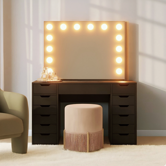 Jenna Hollywood Makeup Vanity Table with LED Mirror in Black, featuring a large bulb-outlined mirror, black drawer-stacked design, soft pink stool, and glass tray with perfumes on a plush carpet.
