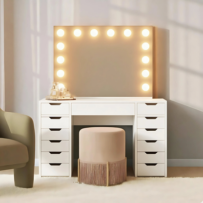 Jenna Hollywood Makeup Vanity Table with LED Mirror in White, featuring a white desk with stacked drawers, a large Hollywood-style mirror with bulbs, a tray with bottles, and a round stool.