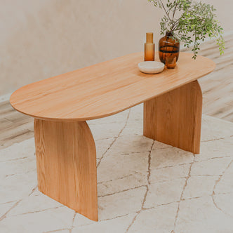 Jillian 180cm Solid Oak Oval Dining Table featuring arched legs, showcased on a coffee table setting with a bowl and candle, highlighting its elegant design and natural wood grain patterns.
