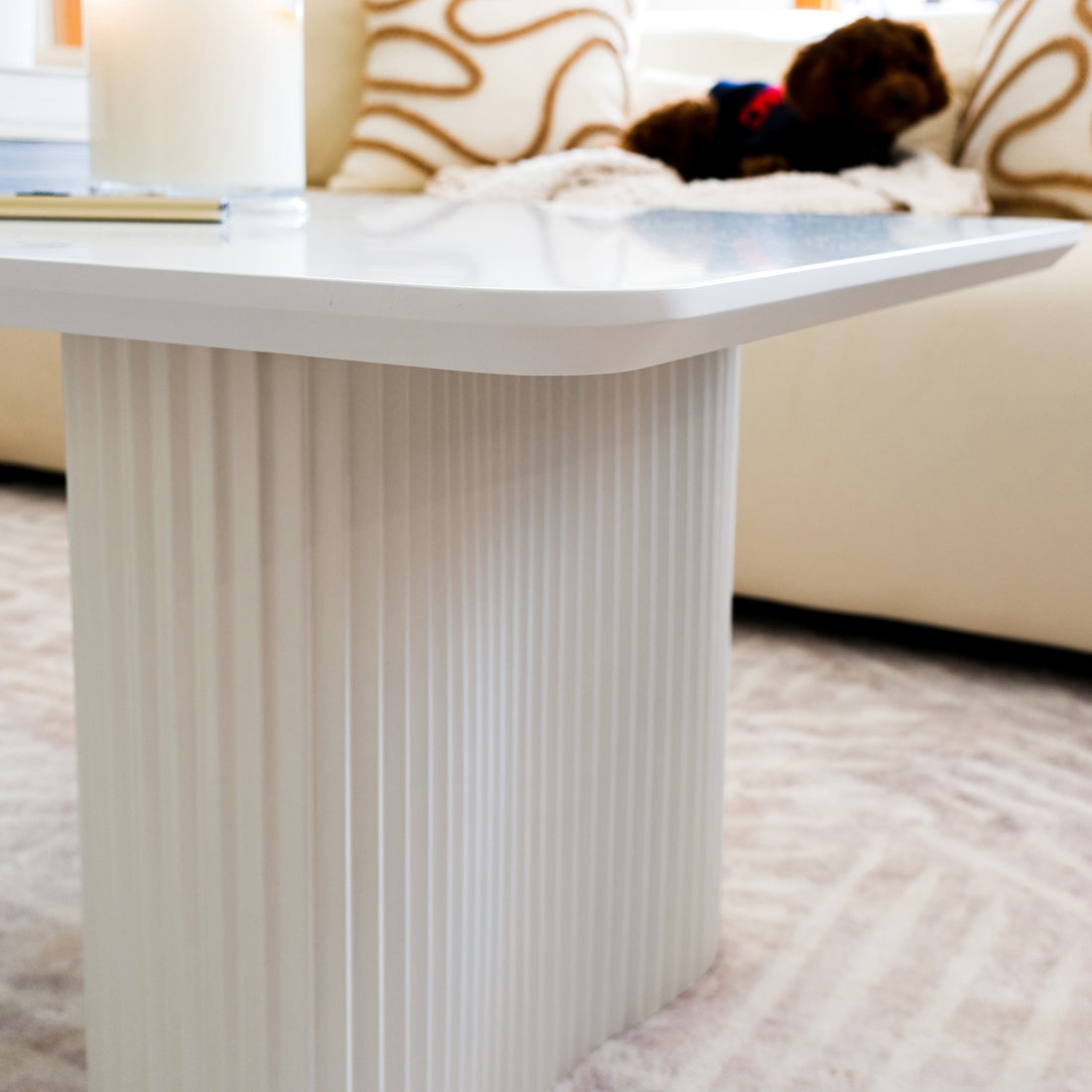 Joyce 120cm Coffee Table with Round Fluted Legs in White, showcasing a sleek rectangular top, elegant fluted pedestal base, with a notebook and candle, against a minimalist living room backdrop.