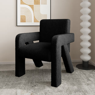 Julie Bouclé Upholstered Accent Chair - Black, featuring a plush bouclé fabric and a curved silhouette in a stylish room, shown with a person seated, highlighting its luxurious comfort and modern design.