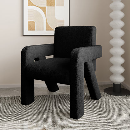 Julie Bouclé Upholstered Accent Chair - Black, featuring a plush bouclé fabric and a curved silhouette in a stylish room, shown with a person seated, highlighting its luxurious comfort and modern design.