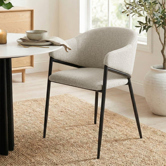 Karin Linen Fabric Dining Chair Set of 2 - Beige, showcasing plush foam cushioning, rounded arms, and a curved backrest, all supported by a powder-coated black metal frame for a stylish, modern look.