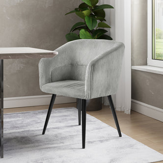 Kirsten Corduroy Fabric Dining Chair Set of 2 in light warm grey features a textured corduroy fabric, curved backrest, and sloping arms, shown beside a table indoors.
