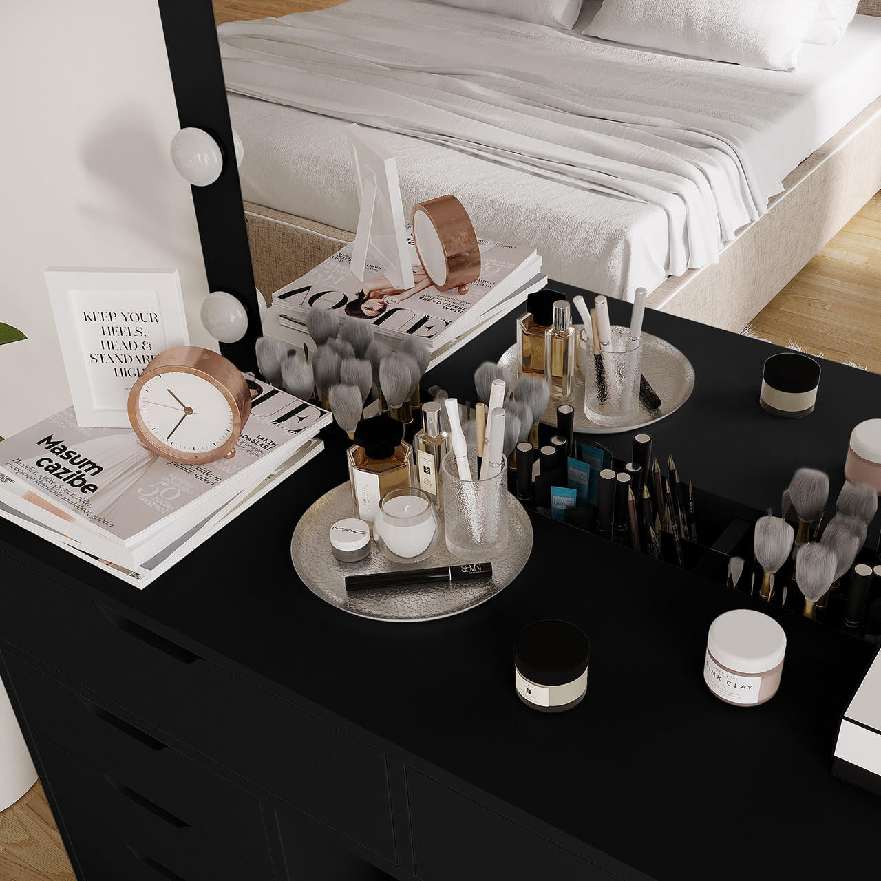 Lassie Hollywood Vanity Dressing Table with Drawers in Black featuring a light-framed mirror with globe bulbs, rose-gold clock, fashion magazines, and trays with perfumes and makeup items.