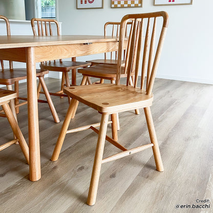 Leigh Solid Oak High-back Dining Chair Natural Set of 2 showcased with a spindle-back design, rounded seat corners, and low footrest, in a modern dining area featuring a matching oak table and chairs.