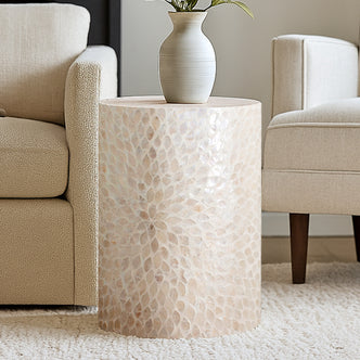 Lulu Mother of Pearl Inlay Side Table in White showcased between cream chairs, featuring a shimmering capiz mosaic surface with a matte ceramic vase and green leaves, exuding elegance and sophistication.
