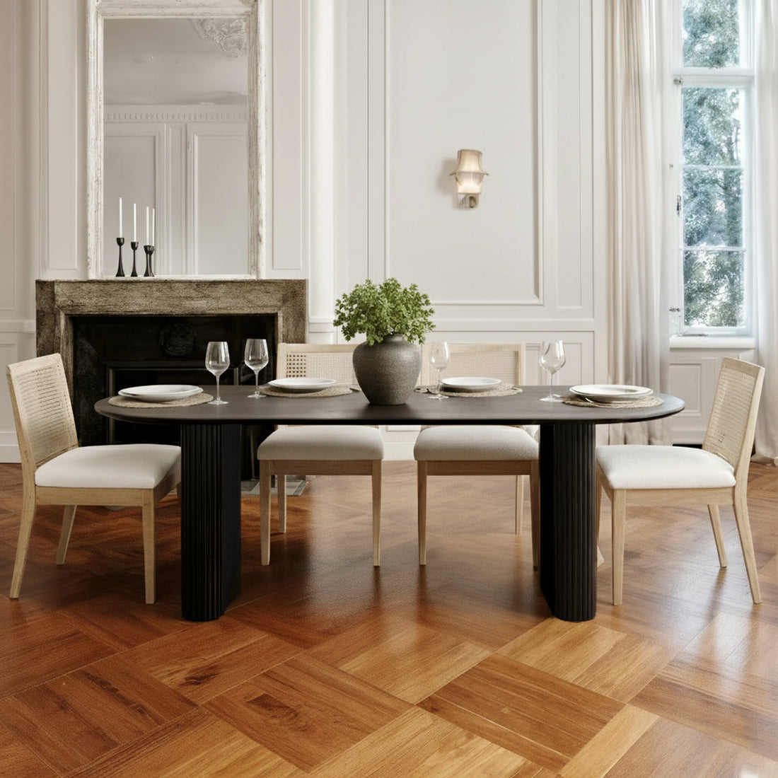 Marciana 8 Seater Fluted Oval Dining Table in Black, showcasing a sleek oval top with a sculptural fluted base, surrounded by light-wood side chairs in a classically styled dining room setting.