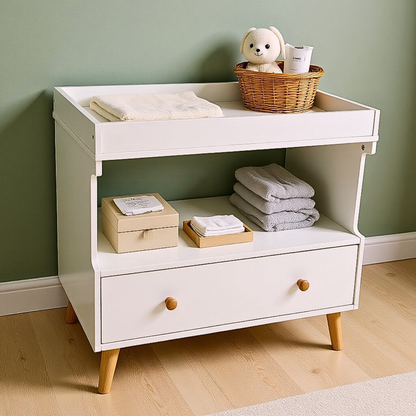 Mariella Solid Pine Baby Change Table with Storage in White, featuring three storage tiers, a bottom drawer, and a top tier with a cream towel and wicker basket, on tapered wooden legs.