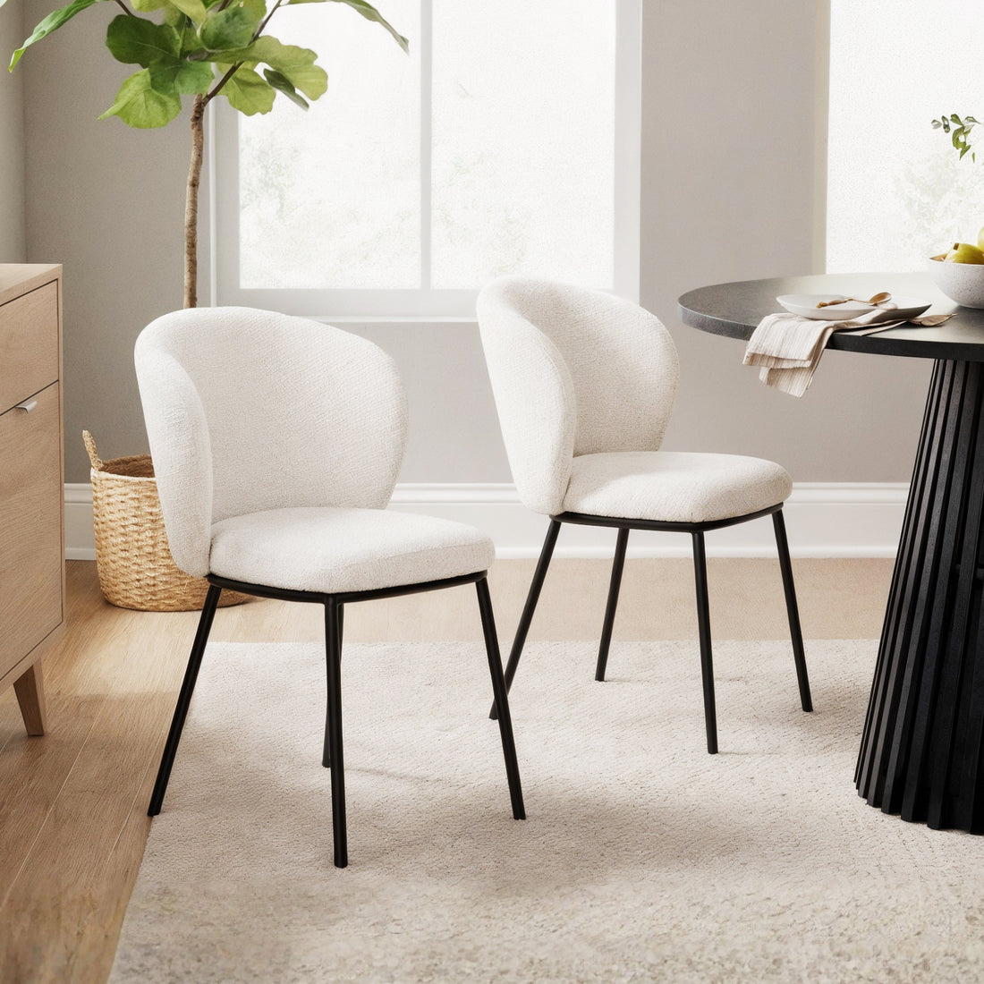 Maveri Boucle Dining Chair Set of 2 in Cream White, featuring gently curved, cushioned backrests and seats in boucle fabric, supported by slim black metal legs, in a neutral-toned dining nook.