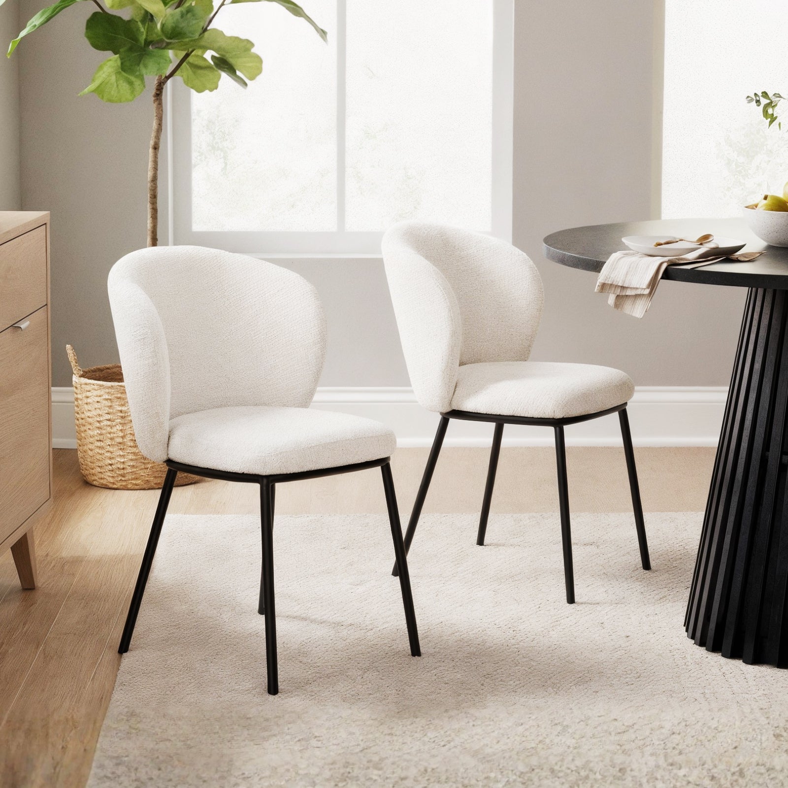 Maveri Boucle Dining Chair Set of 2 in Cream White, featuring gently curved, cushioned backrests and seats in boucle fabric, supported by slim black metal legs, in a neutral-toned dining nook.