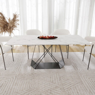 Mavis 180cm Dining Table with Metal Base in White, featuring a rectangular marble-look top and geometric black legs, surrounded by white boucle chairs on a patterned rug, with pomegranates on a platter.