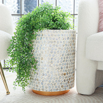 Merry 35cm Mother of Pearl Inlay Side Table in Light Blue, features a mother-of-pearl mosaic pattern, elegantly supporting a trailing green plant, placed between boucle-upholstered chairs on a light rug.