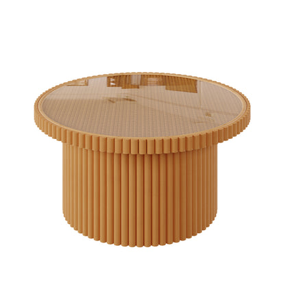 Nylah Natural Rattan Centre Coffee Table in Honey features a round, fluted wooden base with vertical slats and a smooth glass top, showcasing elegant craftsmanship and modern style.