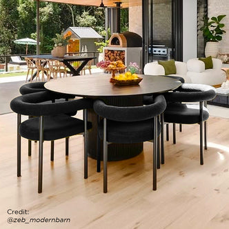 Ohio Curved Boucle Dining Chair Set of 2 in Black, featuring plush bouclé upholstery and sleek black frames, surrounded by a stylish dining area with a round table and fruit arrangements.