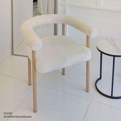 Ohio Curved Boucle Dining Chair Set of 2 in Cream & Oak; features a softly curved backrest and armrests in cream bouclé, with sleek oak-finished legs, set against a minimalist interior.