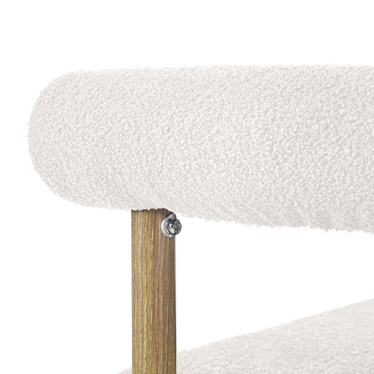 Close-up of Ohio Curved Boucle Dining Chair Set of 2 in Cream & Oak, showing rounded cream boucle cushion, oak support post, and metal bolt securing the cushion rail to the wooden frame.