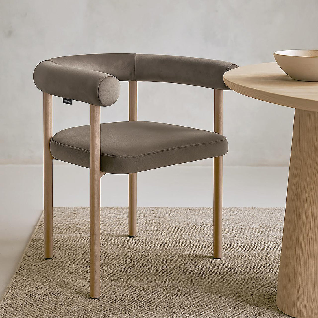 Ohio Velvet Dining Chair w/ Natural Legs Espresso Brown Set of 2 on a natural-fiber rug, featuring a curved backrest and seat in muted taupe/grey fabric, with light-wood legs beside a wooden table edge.