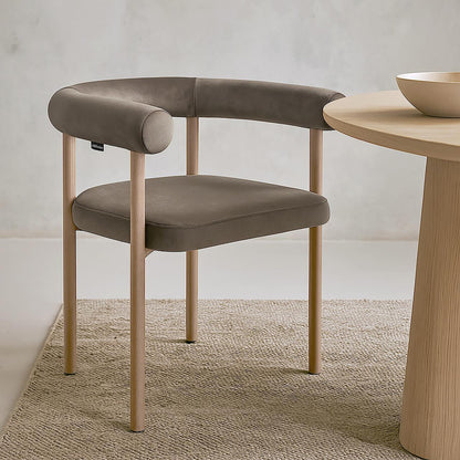 Ohio Velvet Dining Chair w/ Natural Legs Espresso Brown Set of 2 on a natural-fiber rug, featuring a curved backrest and seat in muted taupe/grey fabric, with light-wood legs beside a wooden table edge.