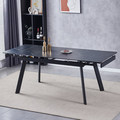Rheed 197cm Extendable Ceramic Dining Table in Black with a faux-marble top, angled legs, gold-tone candleholders, and cured meat slices, set in a modern dining room with a black shelving unit.