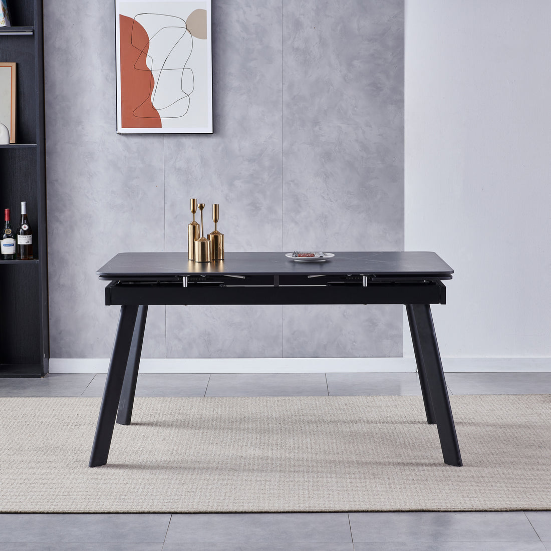 Rheed 197cm Extendable Ceramic Dining Table in Black, featuring a smooth tabletop with splayed legs, adorned with brass vases and a small snack plate, set on a woven rug.