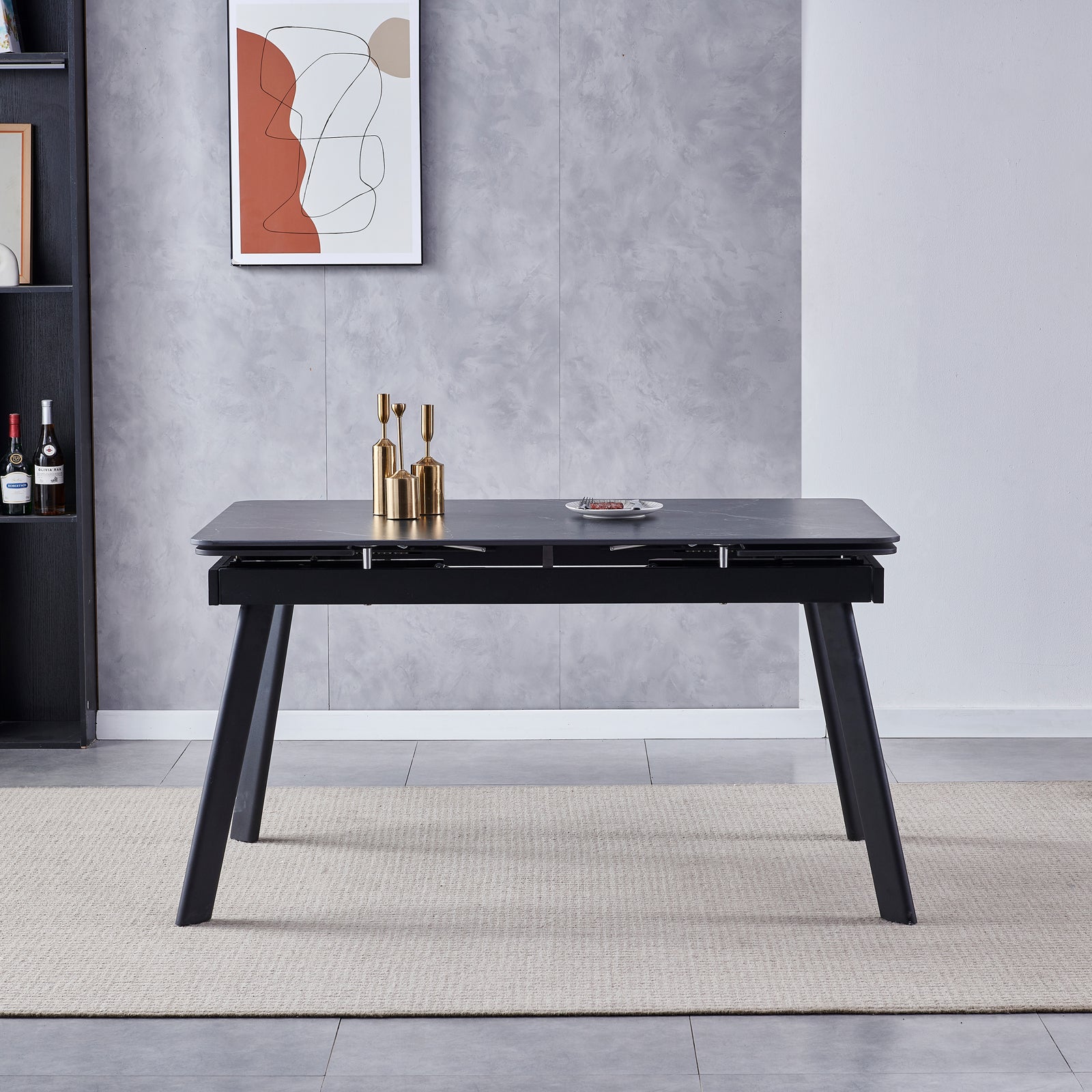 Rheed 197cm Extendable Ceramic Dining Table in Black, featuring a smooth tabletop with splayed legs, adorned with brass vases and a small snack plate, set on a woven rug.