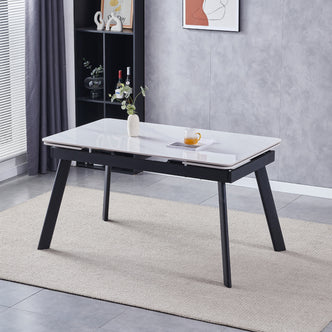 Rheed 197cm Extendable Ceramic Porcelain Dining Table White with glossy marble-look top, black metal legs, styled with a ceramic vase, book, and glass mug on a woven rug.