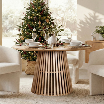 Riri 120cm Round Fluted Dining Table in Oak features a sculptural slatted base, set with elegant holiday decor including eucalyptus sprigs, pinecones, and holly berries, evoking a modern-rustic holiday ambiance.