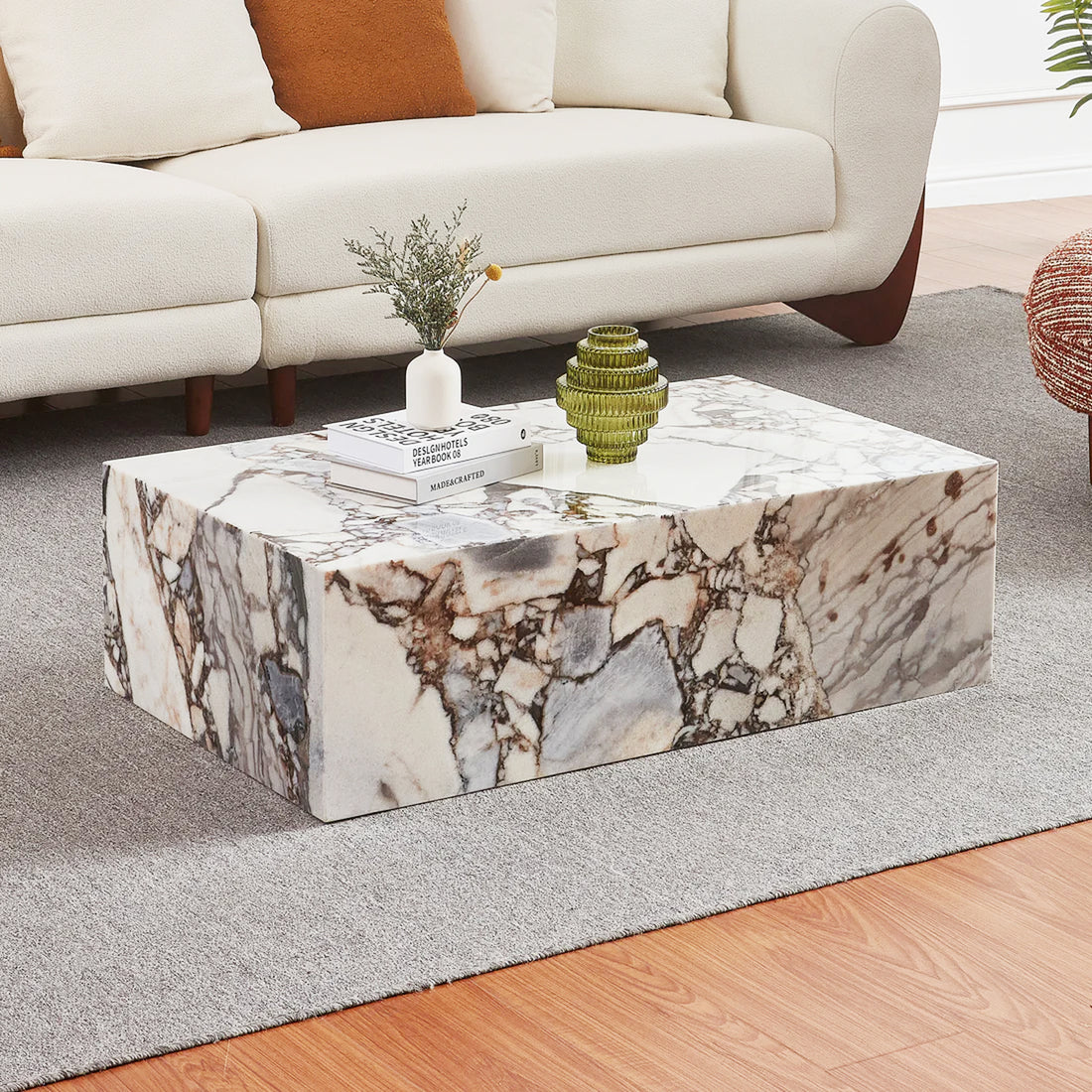 Solene 100cm Coffee Table in Real Blue Galaxy Marble with distinctive veining, topped with design books, vase, and decorative vessel, set in a contemporary living room with an off-white sofa.