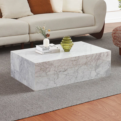 Solene 100cm Coffee Table in Real Carrara Marble, showcased with natural veining and a clean, low-profile design, accompanied by books and vases on a light gray rug in a modern living room.
