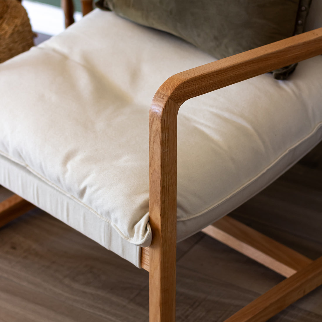 Tilly Linen Hardwood Arm Chair showcasing a close-up of its durable oak frame and sleek wooden armrest, complemented by plush cushions, epitomizing stylish comfort and minimalist design for modern interiors.