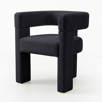 Utah Bouclé Curved 3 Legged Accent Chair in Black, featuring a sculptural U-shaped design, deep charcoal nubby fabric, and thick block-like legs for a minimalist, geometric look with tactile texture.