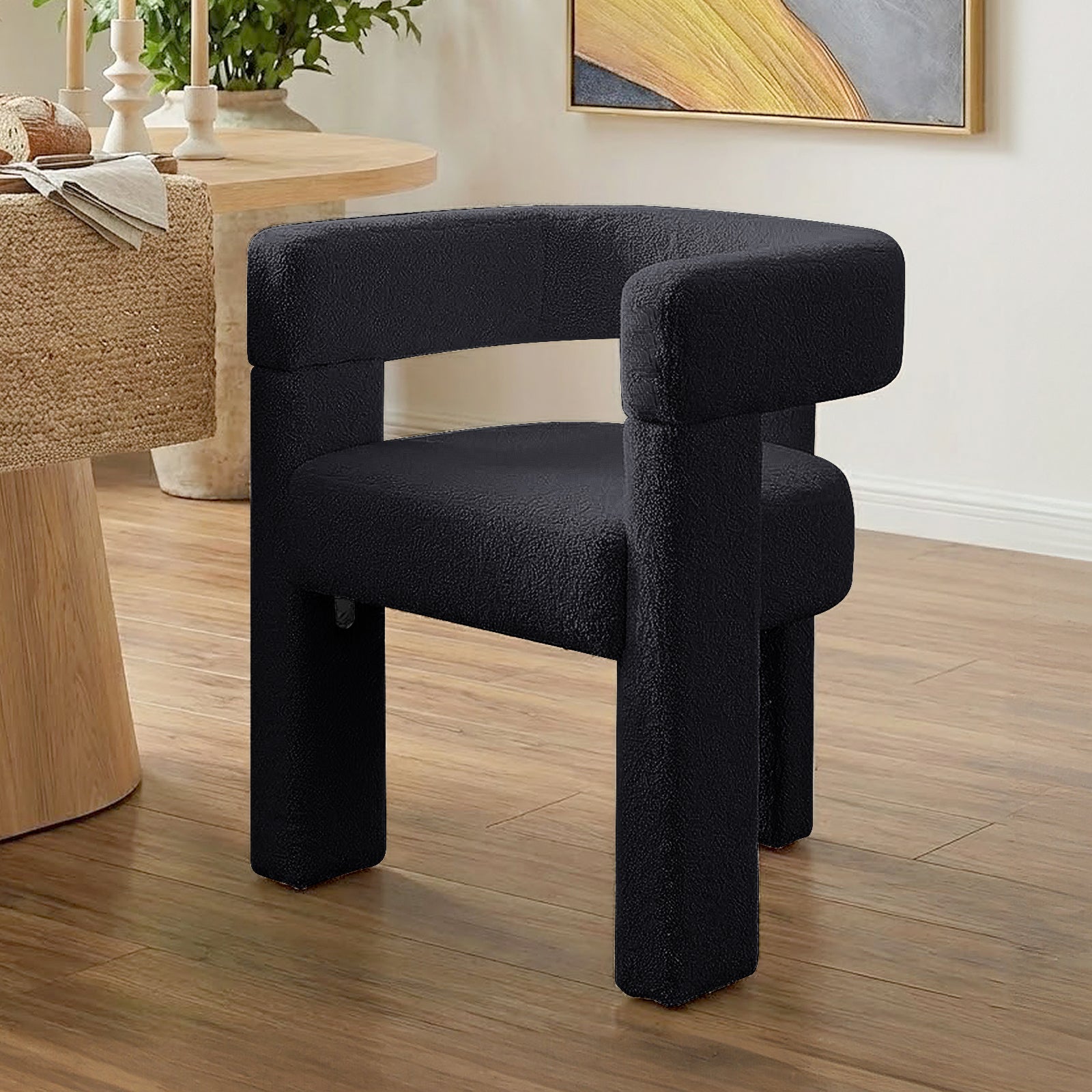 Utah Bouclé Curved 3 Legged Accent Chair in Black features a rounded open backrest, chunky legs, and luxurious bouclé upholstery, perfectly complementing modern interiors with its unique silhouette and plush comfort.