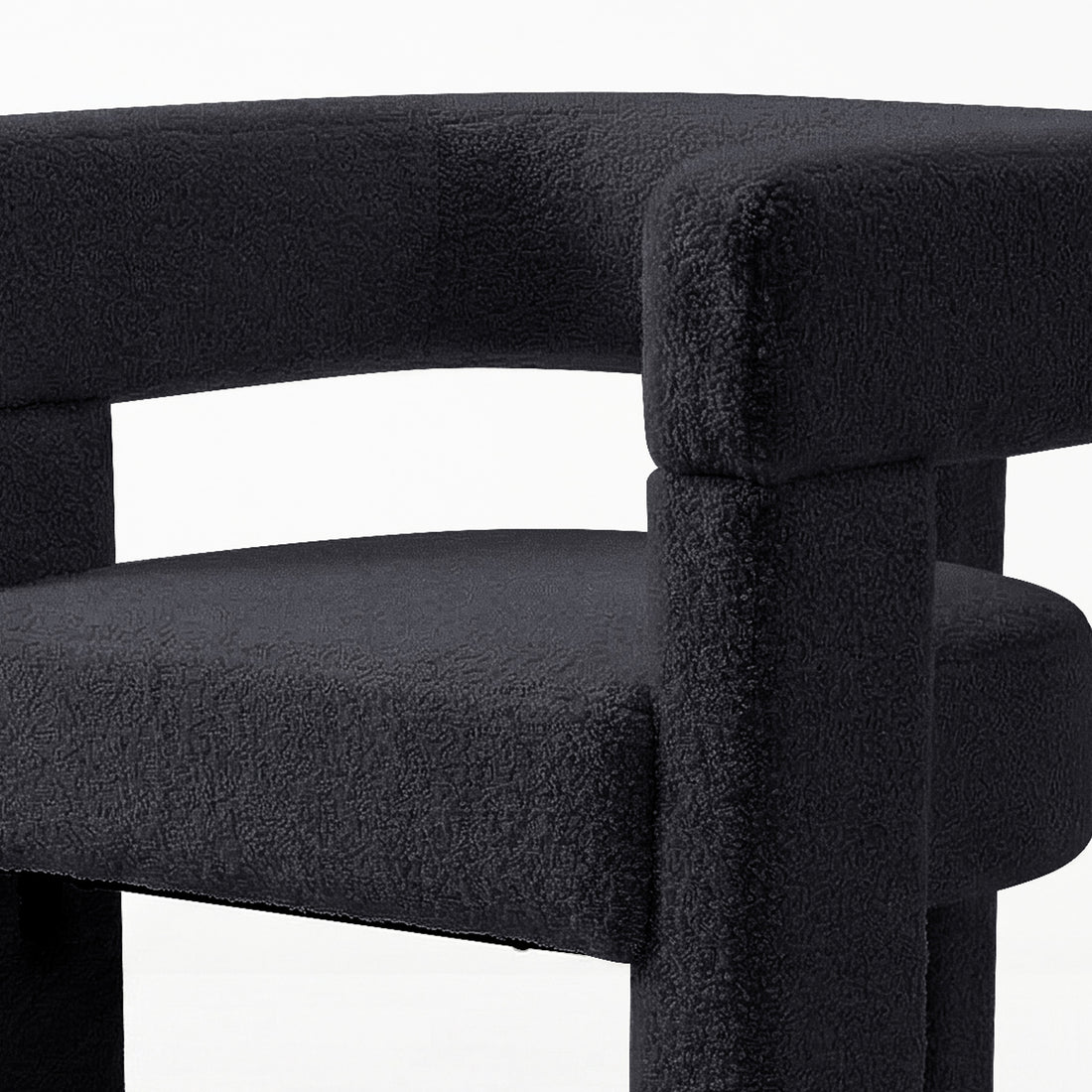 Utah Bouclé Curved 3 Legged Accent Chair in Black featuring a modern tubular design with textured bouclé fabric, showcasing part of the curved backrest, rounded seat, and thick cylindrical supports.