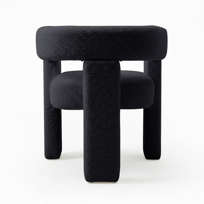 Utah Bouclé Curved 3 Legged Accent Chair in Black, featuring a modern, sculptural design with plush bouclé upholstery and three chunky cylindrical legs, offering both comfort and a striking focal point.