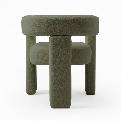 Utah Bouclé Curved 3 Legged Accent Chair in Green, featuring a plush, round cushioned top and four chunky cylindrical legs, all upholstered in muted green bouclé fabric, creating a modern, minimalist look.