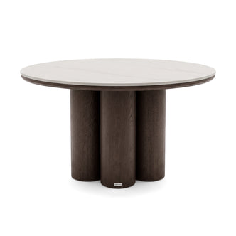 Round dining table with light top and dark cylindrical base on white background